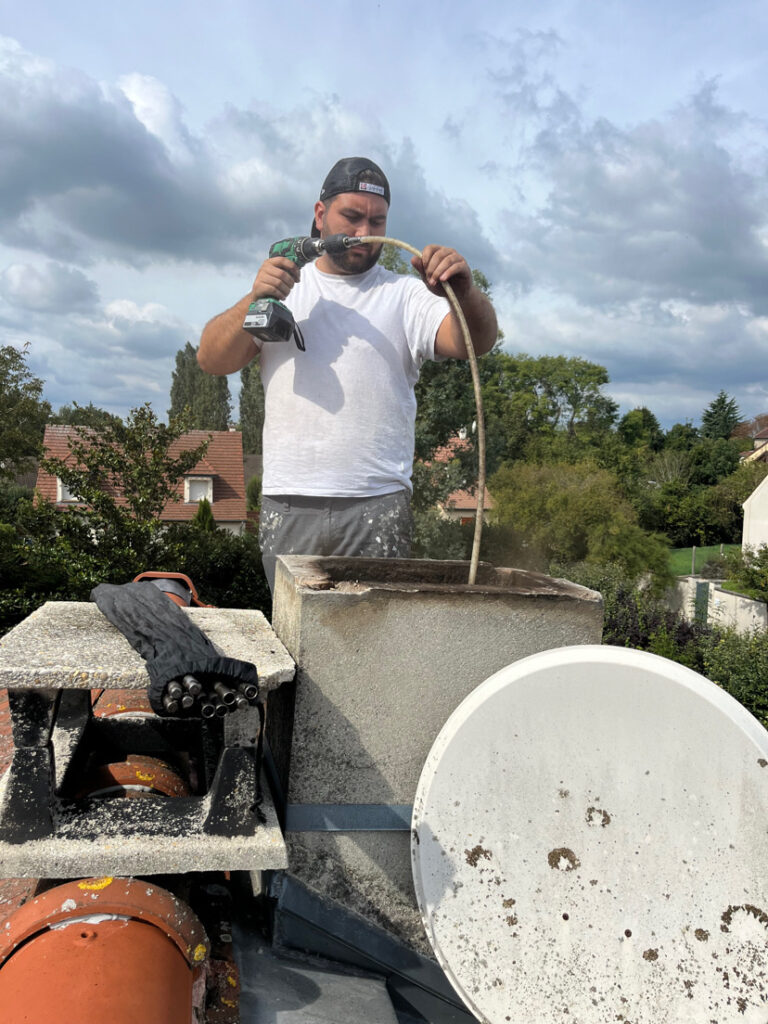 Ramonage Chelles - Un ramoneur effectue un débistrage mécanique d’un conduit de cheminée pour éliminer les goudrons accumulés.