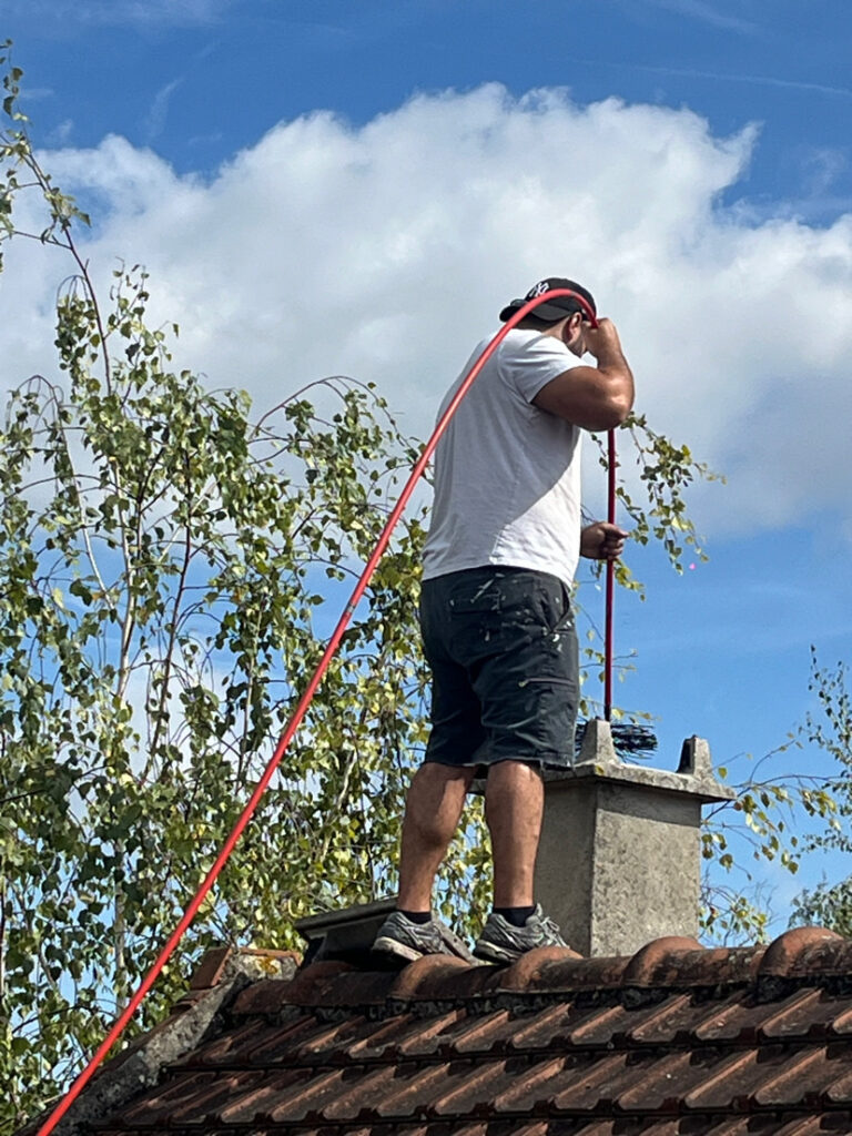 Ramonage Chelles - Un ramoneur en action sur une toiture effectue un ramonage traditionnel avec hérisson.